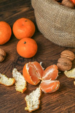 Olgun, lezzetli ve sulu portakallar, mandalinalar ve masada cevizler..