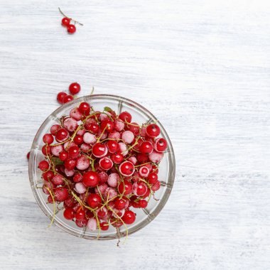 Beyaz ahşap bir masadaki cam vazoda donmuş kırmızı üzümler. Yakın plan. Doğal ve sağlıklı vitamin açısından zengin donmuş dut..