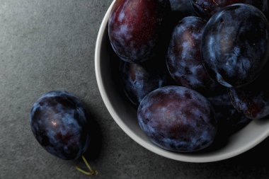 Koyu arkaplanda bir kasede mavi erik. Üst Manzara. Mesaj için yer. Fotokopi alanı olan meyve arkaplanı. Durgun yaşam yemeği.