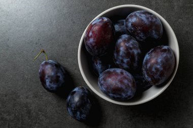 Koyu arkaplanda bir kasede mavi erik. Üst Manzara. Mesaj için yer. Fotokopi alanı olan meyve arkaplanı. Durgun yaşam yemeği.