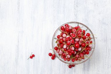 Beyaz ahşap bir masadaki cam vazoda donmuş kırmızı üzümler. Yakın plan. Doğal ve sağlıklı vitamin açısından zengin donmuş dut..
