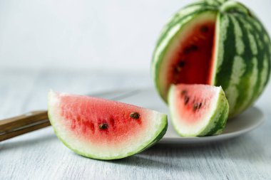Tam ve dilimlenmiş karpuz, ahşap masa arkasında ballı karpuz. Çok sağlıklı, doğal, vejetaryen yiyecekler..