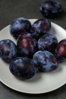 Koyu arkaplanda bir tabakta mavi erik. Mesaj için yer. Fotokopi alanı olan meyve arkaplanı. Durgun yaşam yemeği.