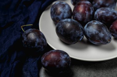 Koyu arkaplanda bir tabakta mavi erik. Mesaj için yer. Fotokopi alanı olan meyve arkaplanı. Durgun yaşam yemeği.