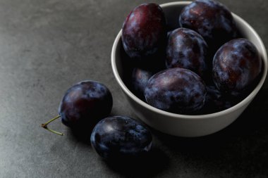 Koyu arkaplanda bir kasede mavi erik. Mesaj için yer. Fotokopi alanı olan meyve arkaplanı. Durgun yaşam yemeği.