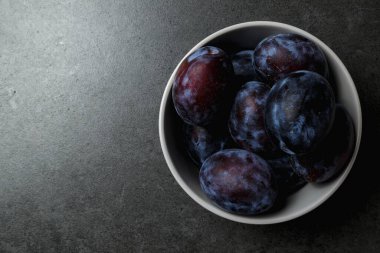 Koyu arkaplanda bir kasede mavi erik. Üst Manzara. Mesaj için yer. Fotokopi alanı olan meyve arkaplanı. Durgun yaşam yemeği.