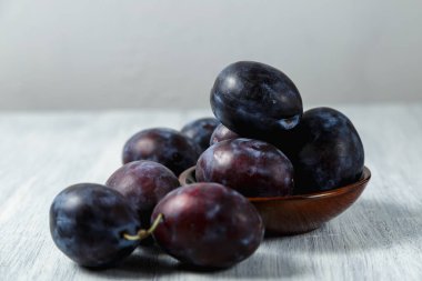 Ahşap bir masada tabakta mavi erik. Mesaj için yer. Fotokopi alanı olan meyve arkaplanı. Durgun yaşam yemeği.