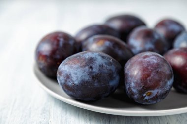 Ahşap bir masada tabakta mavi erik. Mesaj için yer. Fotokopi alanı olan meyve arkaplanı. Durgun yaşam yemeği.