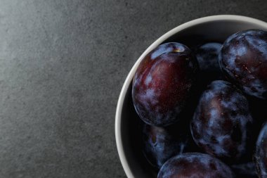 Koyu arkaplanda bir kasede mavi erik. Üst Manzara. Mesaj için yer. Fotokopi alanı olan meyve arkaplanı. Durgun yaşam yemeği.