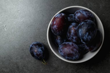 Koyu arkaplanda bir kasede mavi erik. Üst Manzara. Mesaj için yer. Fotokopi alanı olan meyve arkaplanı. Durgun yaşam yemeği.