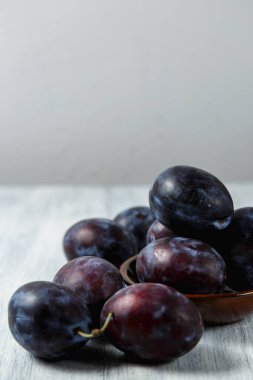 Ahşap bir masada tabakta mavi erik. Mesaj için yer. Fotokopi alanı olan meyve arkaplanı. Durgun yaşam yemeği.