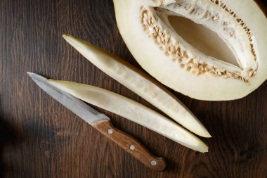 Tam ve dilimlenmiş kavun, ahşap masa zemininde ballı kavun. Çok sağlıklı, doğal, vejetaryen yiyecekler..