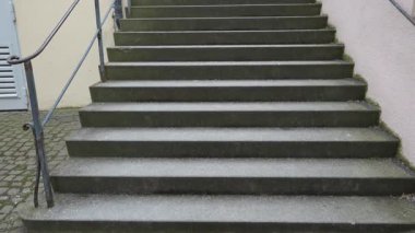 Yukarı çıkan yosunlu beton kaplama merdivenler, Metal parmaklıklı sessiz şehir avlusu ve kaldırım taşları, yosun büyüyen rutubetli hava yüzeyleri, sessiz gri palet, mimari simetri