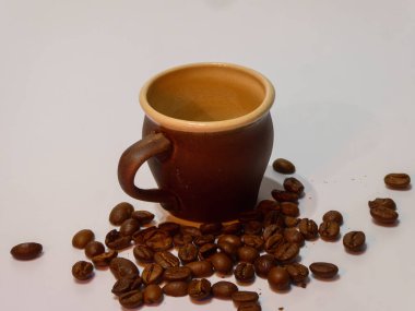 Temiz beyaz bir yüzey üzerinde taze kavrulmuş kahve çekirdekli toprak kap..