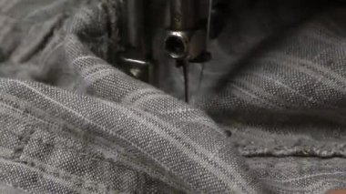 Gri keten kumaş dikişli eski bir dikiş makinesinin detaylı yakın çekimi.