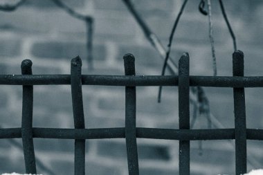 Vintage style photo of a rusty metal fence in winter with artistic grain and cinematic mood