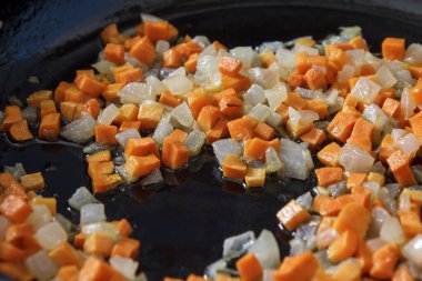 Kızartma tavasında sotelenmiş havuç ve soğan işlem süreci. Sağlıklı yemek pişirmek için yağda kızartılmış sebzeleri kapatın..