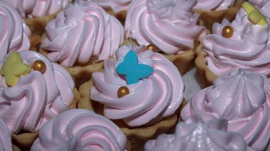 Pembe kıvrımlı ve renkli dekorasyonlu bir sürü tatlı turta. Şenlikli bir etkinlik ya da fırın gösterisi için lezzetli kekler yakın plan..