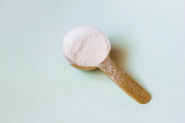測定スプーンの白いコラーゲンタンパク質粉末を背景に散在 — ストック写真