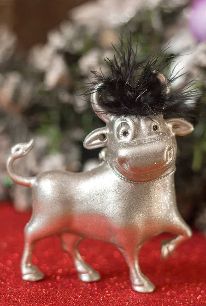 Symbol of the year 2021 metal bull christmas tree toy and christmas tree on red glowing background, copy space for text