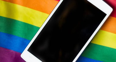 Gökkuşağı lgbt bayrağı ve kot arka planında beyaz akıllı telefon, lezbiyen, gey ve biseksüel hoşgörü ve özgürlük teması