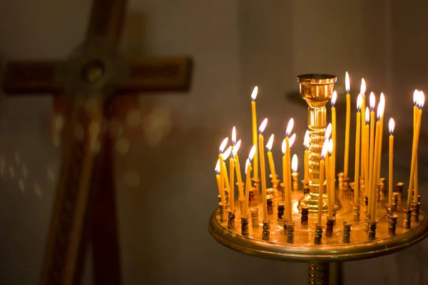 Candles burning in the church church against the background of the cross, prayer for health and peace of the soul, church interior, Christian holiday
