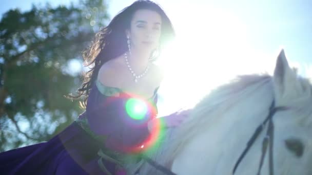 Молодая женщина сидит на белом коне на открытом воздухе — стоковое видео