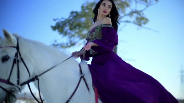 Молода жінка сидить на білому коні на відкритому повітрі — стокове відео