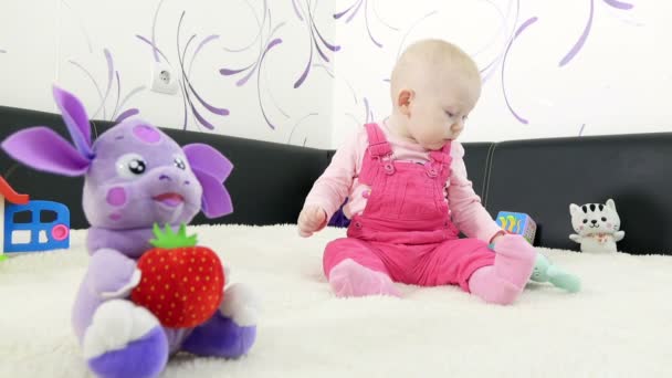 Baby Mädchen sitzt auf dem Sofa und spielt Spielzeug, kleines Kind frühkindliche Bildung Konzept. — Stockvideo