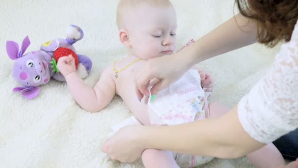 Мама меняет подгузник маленького ребенка — стоковое видео