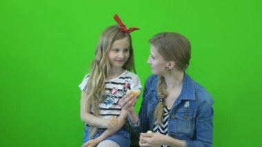 Chromakey görüntüleri anne ve kızı bir mandalina yeşil bir arka plan üzerinde yemek