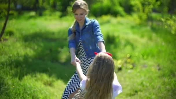 Jonge moeder met haar dochter spelen in een park voorjaarsbijeenkomst — Stockvideo