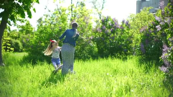 Jovem mãe com sua filha brincando em um parque de primavera — Vídeo de Stock