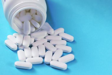 Mavi tıbbi geçmişe yayılmış beyaz haplar.