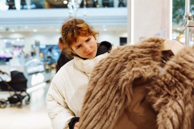 Mağazada moda kürk giyen kızıl saçlı çekici genç bir kadının portresi. pozitif gülümseme