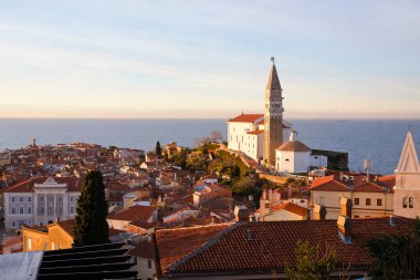 Eski şehir Piran 'ın tarihi merkezinin kırmızı çatıları, günbatımı gökyüzüne ve Adriyatik denizine karşı ana kilise. Hava manzarası, Slovenya