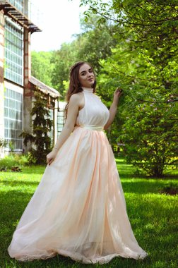 Güneşli bir günde bahar bahçesinde yürüyen çekici genç bir kadının portresi. Bahar arka planı. Kadın Günü. Tebrik kartı