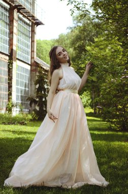 Güneşli bir günde bahar bahçesinde yürüyen çekici genç bir kadının portresi. Bahar arka planı. Kadın Günü. Tebrik kartı