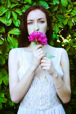 Bahar bahçesinde çiçek açan pembe şakayıklı genç bir kadının portresi. Bahar arka planı. Kadın Günü. Tebrik kartı. 