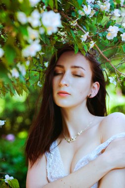 Bahar bahçesinde, güzel kokulu yasemin çalılarıyla genç ve çekici bir kadının portresi. Bahar arka planı. Kadın Günü. Tebrik kartı.