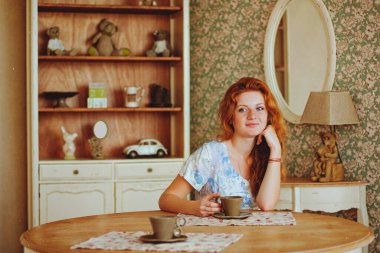 Evde güneşli bir sabahta çilli, kahve içen genç kızıl saçlı kadının portresi. Doğal güzellik. Kadın Günü. Durgun hayat.