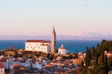 Eski şehir Piran 'ın tarihi merkezinin kırmızı çatıları, günbatımı gökyüzüne ve Adriyatik denizine karşı ana kilise. Hava manzarası, Slovenya