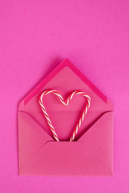 Şenlikli pembe arka plan. Zarflı tatlı şekerler. Sevgi. Sevgililer Günü. 14 Şubat. Düz yatış, üst görünüm.