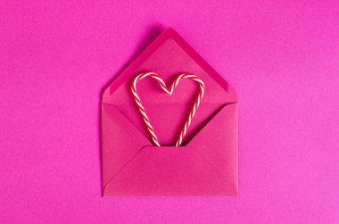 Şenlikli pembe arka plan. Zarflı tatlı şekerler. Sevgi. Sevgililer Günü. 14 Şubat. Düz yatış, üst görünüm.