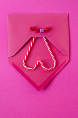 Şenlikli pembe arka plan. Zarfın içinde tatlı şekerler var. Üzerinde 
