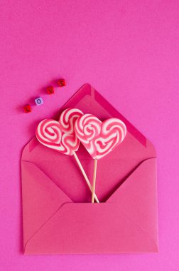 Şenlikli pembe arka plan. Zarfın içinde tatlı şekerler var. Üzerinde 