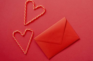 Kırmızı arka plan şenliği. Zarflı tatlı şekerler. Sevgi. Sevgililer Günü. 14 Şubat. Düz yatış, üst görünüm.