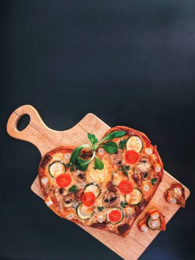 Lezzetli vejetaryen kalbi siyah zemin üzerinde Sevgililer Günü için domatesli, sebzeli ve peynirli pizza şeklinde. Romantik aşkın yaratıcı yemek konsepti. Üst manzara, düz uzanma.