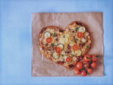 Lezzetli vejetaryen kalbi domatesli, sebzeli ve peynirli pizza. Mavi arka planda Sevgililer Günü için. Romantik aşkın yaratıcı yemek konsepti. Üst manzara, düz uzanma.