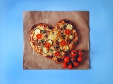Lezzetli vejetaryen kalbi domatesli, sebzeli ve peynirli pizza. Mavi arka planda Sevgililer Günü için. Romantik aşkın yaratıcı yemek konsepti. Üst manzara, düz uzanma.